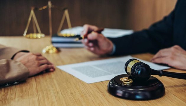 Divorce lawyer in Dubai reviewing paperwork with a gavel and wedding rings on the desk