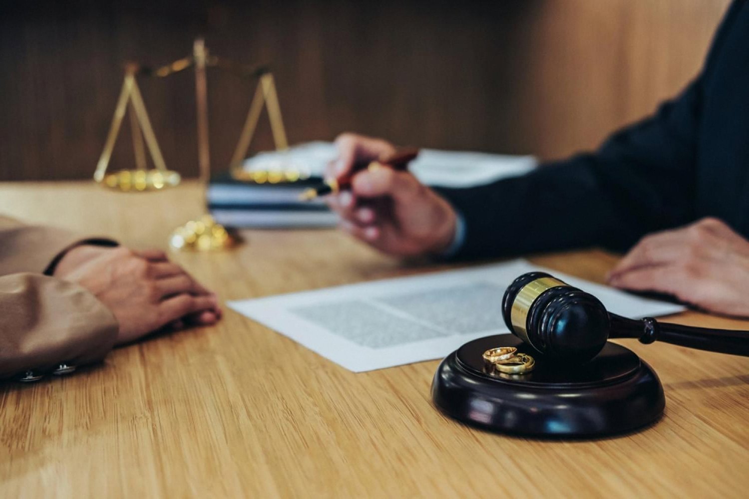Divorce lawyer in Dubai reviewing paperwork with a gavel and wedding rings on the desk